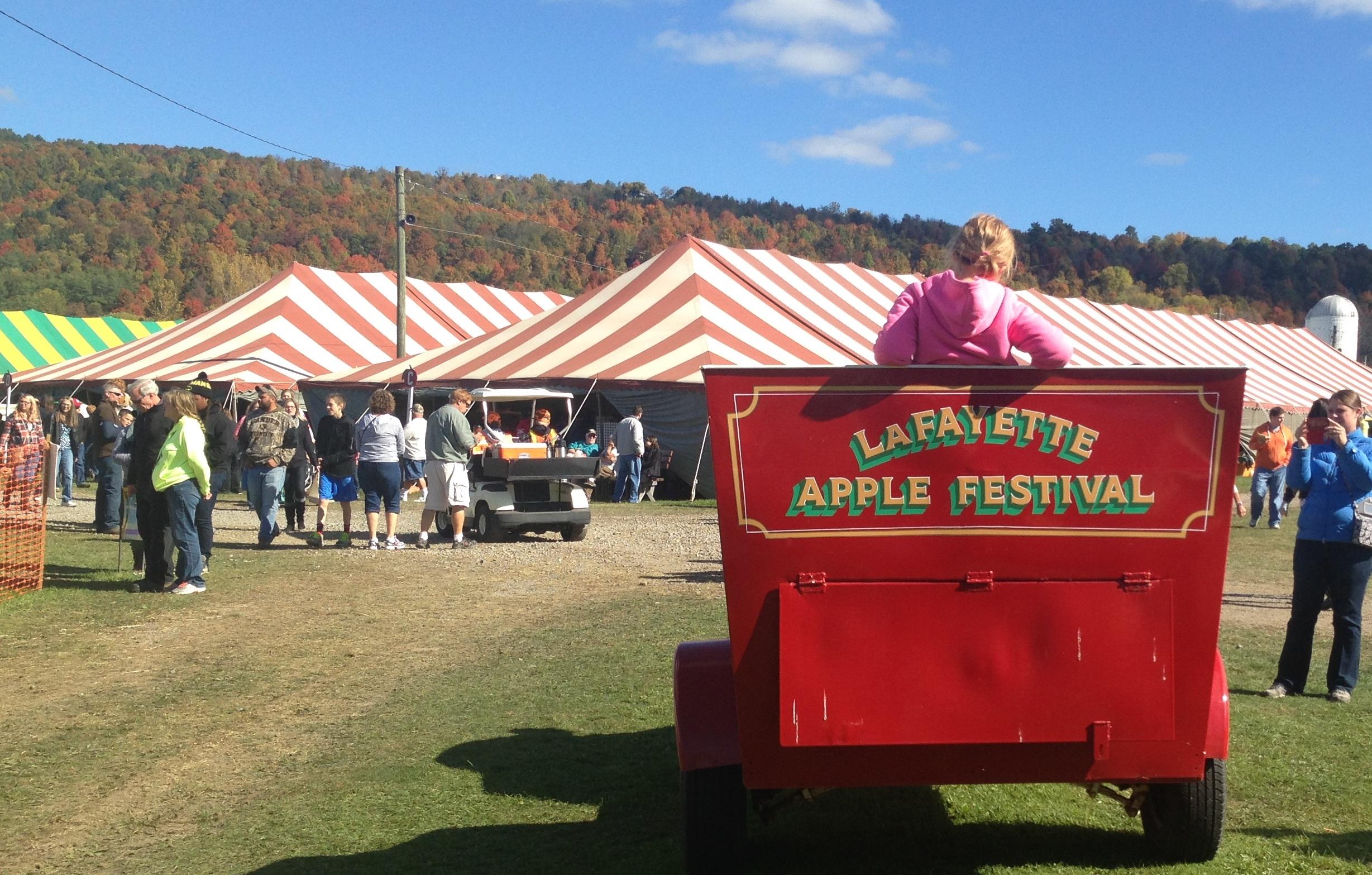 Lafayette Apple Festival sign with festival tents and guests during fall near Skaneateles, New York.