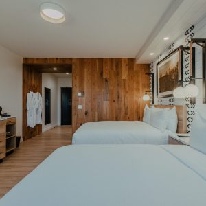 Double Queen guest room with two beds, wood accents, patterned wall detail, and dresser at Skaneateles Fields Resort & Spa.