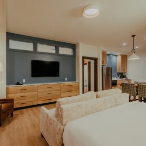 Family Room with bed, sofa, dining area, dresser, and television at Skaneateles Fields Resort & Spa.